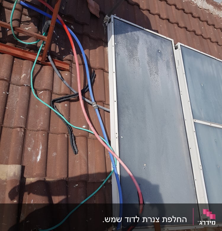 צינורות צבעוניים מחוברים לדוד שמש על גג רעפים